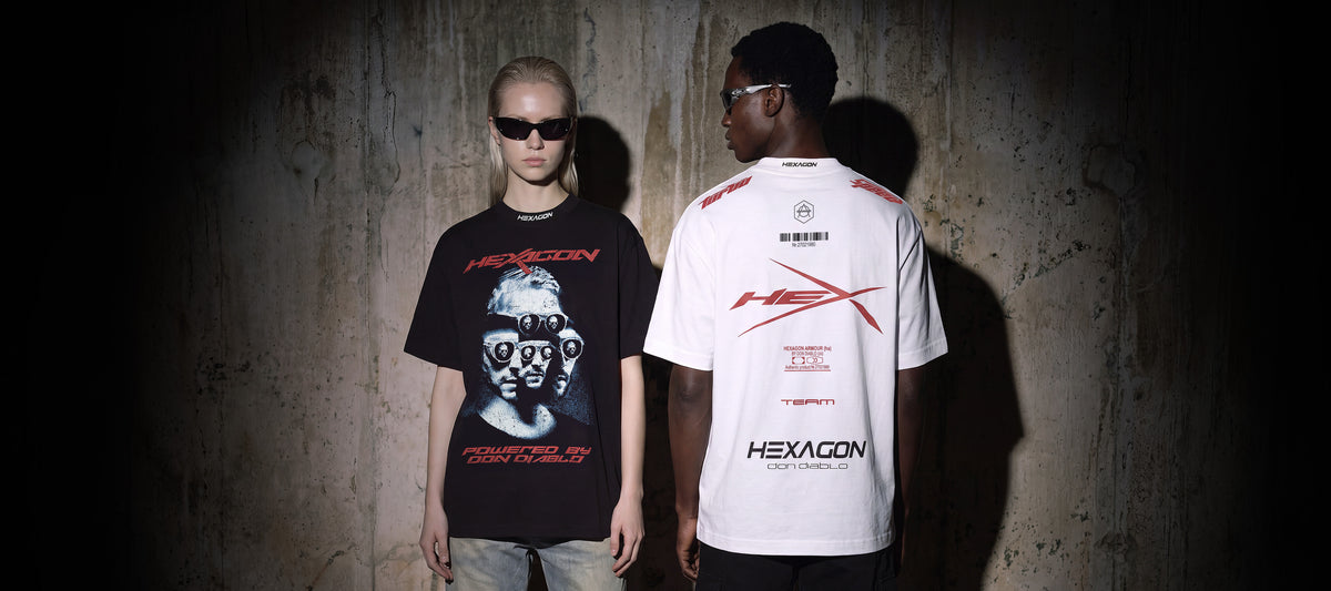 Two models standing against a dark concrete wall, showcasing a black graphic t-shirt on the left and a white t-shirt with red graphics on the right. Both shirts feature the brand name 'HEXAGON'.